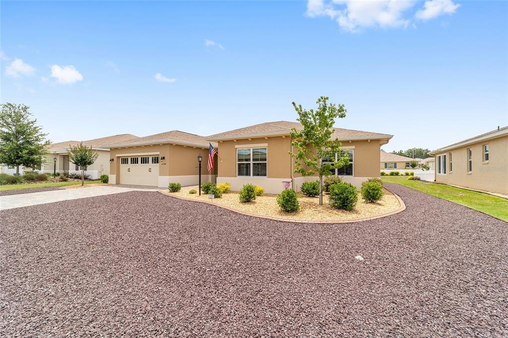A tan single-story house with a gravel front yard and a two-car garage — 10344 SW 98TH PLACE ROAD, OCALA, FL