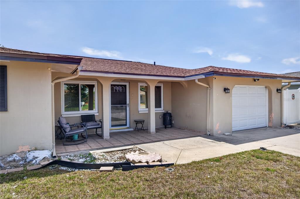 A single-story house exterior features a covered front porch, a garage, and a lawn — 10237 OAK HILL DRIVE, PORT RICHEY, FL