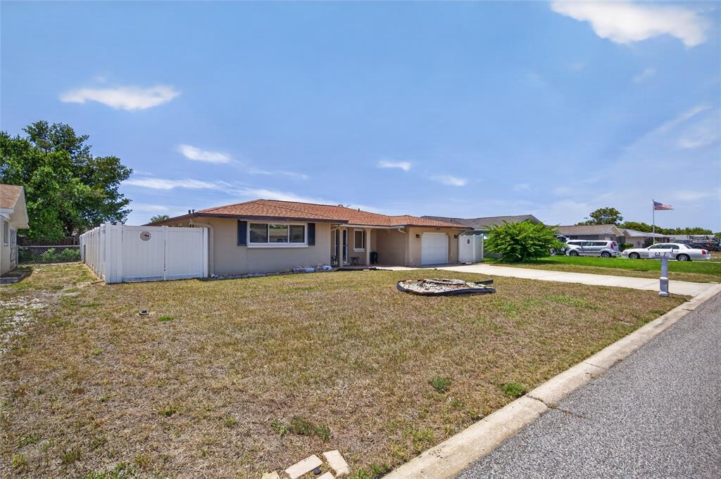 A single-story house with a tan exterior, a brown roof, and a front lawn — 10237 OAK HILL DRIVE, PORT RICHEY, FL