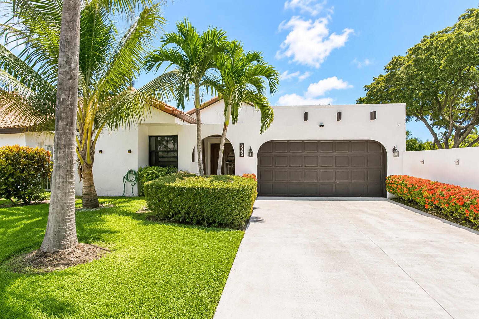 A white house with a brown garage door, palm trees, and a manicured lawn — 7678 Solimar Circle, Boca Raton FL 33433, BOCA RATON, FL