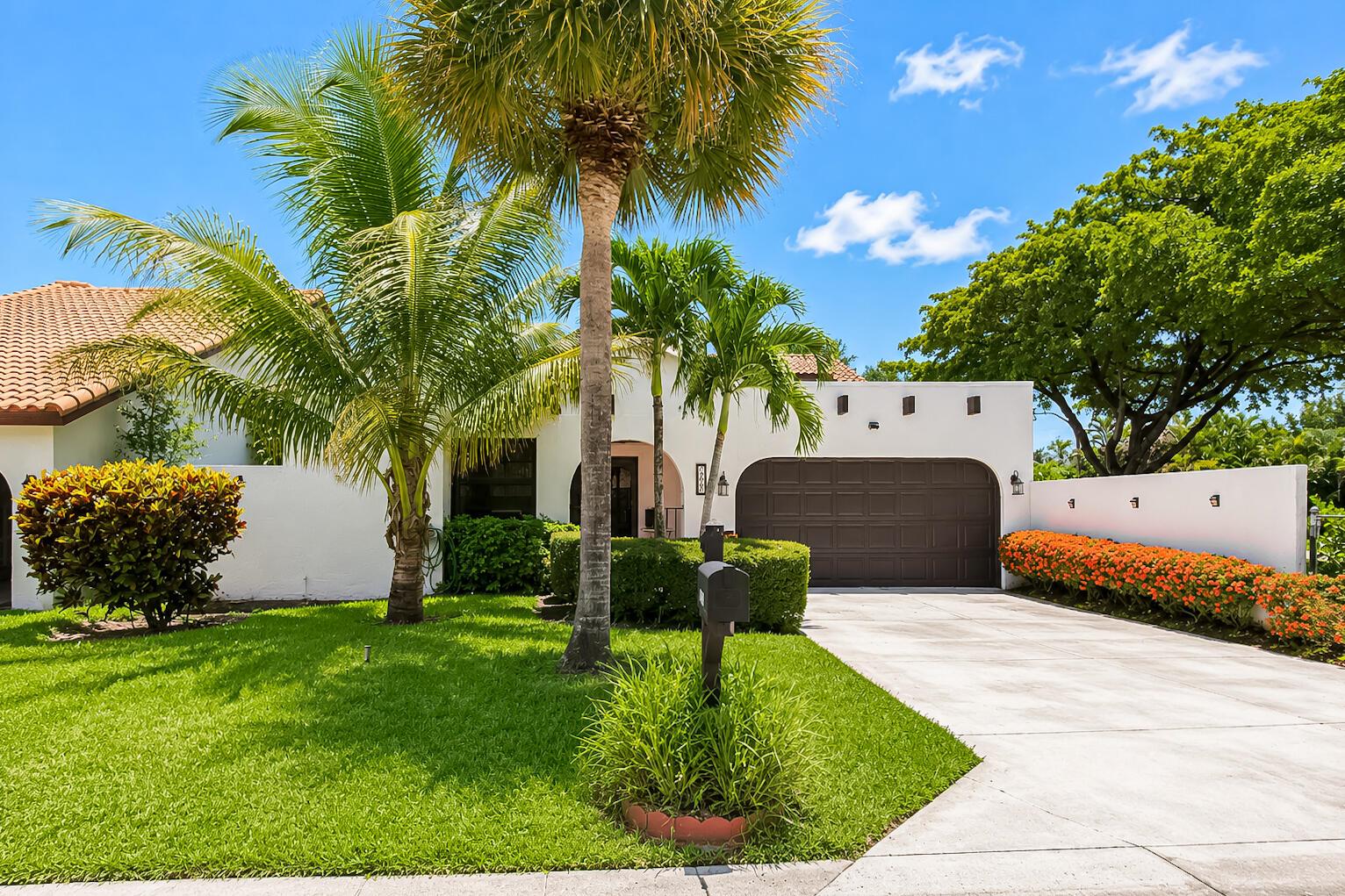 A white house with a brown garage door, palm trees, and a landscaped front yard — 7678 Solimar Circle, Boca Raton FL 33433, BOCA RATON, FL