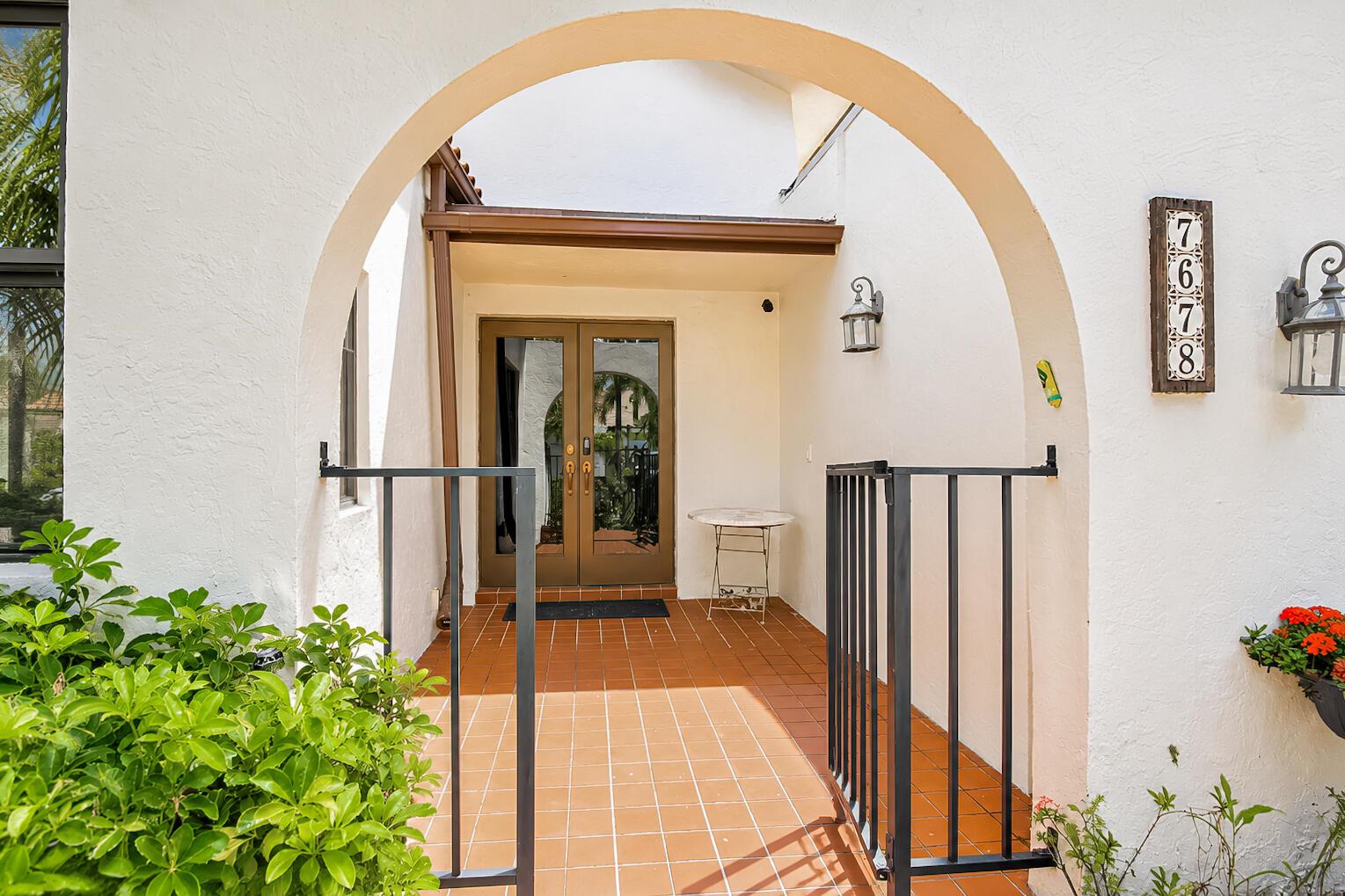 The exterior entryway features a tiled patio, a black metal gate, and a double-door entrance — 7678 Solimar Circle, Boca Raton FL 33433, BOCA RATON, FL
