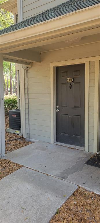 A dark brown front door with the number 102 is located under a covered porch — 6052 WESTGATE DRIVE UNIT 102, ORLANDO, FL