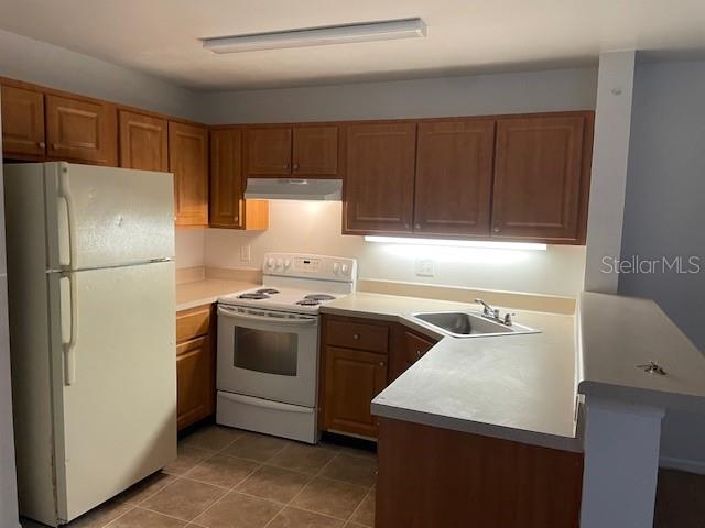 A kitchen features wooden cabinets, a white refrigerator, a white stove, and a laminate countertop — 6052 WESTGATE DRIVE UNIT 102, ORLANDO, FL