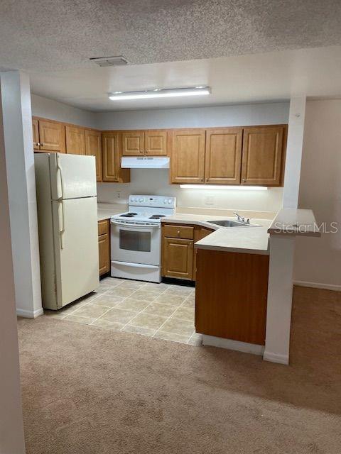 A kitchen features light wood cabinets, a white refrigerator, and a tiled floor — 6052 WESTGATE DRIVE UNIT 102, ORLANDO, FL