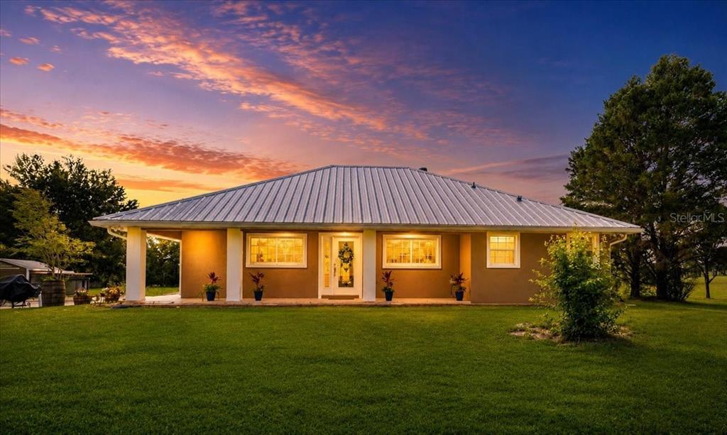 A single-story house with a metal roof and a covered front porch at sunset — 14681 NW 232ND STREET, HIGH SPRINGS, FL