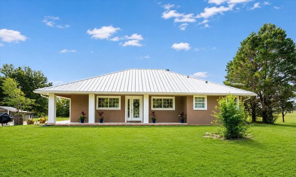 A single-story house with a metal roof and a covered front porch sits on grass — 14681 NW 232ND STREET, HIGH SPRINGS, FL