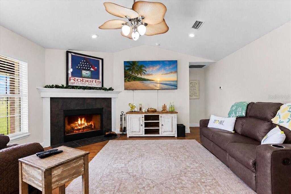 A living room features a fireplace, a wall-mounted television, and a brown leather sofa — 14681 NW 232ND STREET, HIGH SPRINGS, FL