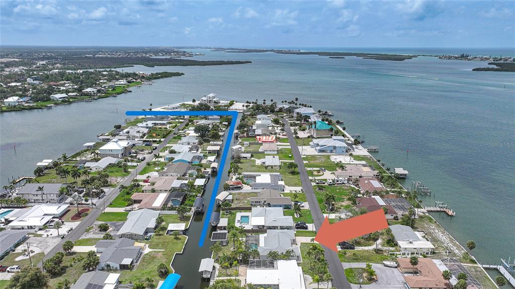 An aerial view shows a coastal neighborhood with houses, a canal, and a large bay — 1433 LEMON BAY DRIVE, ENGLEWOOD, FL