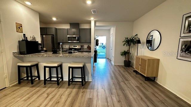 A kitchen with gray cabinets and a breakfast bar overlooks a dining area with flooring — 710 STONEY POINT CIRCLE, DAVENPORT, FL
