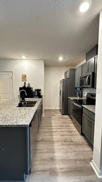 A kitchen features dark gray cabinets, granite countertops, stainless steel appliances, and wood-look flooring — 710 STONEY POINT CIRCLE, DAVENPORT, FL
