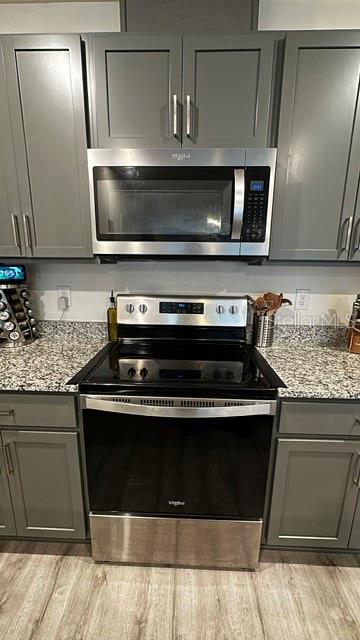 A kitchen features gray cabinets, stainless steel appliances, and granite countertops — 710 STONEY POINT CIRCLE, DAVENPORT, FL