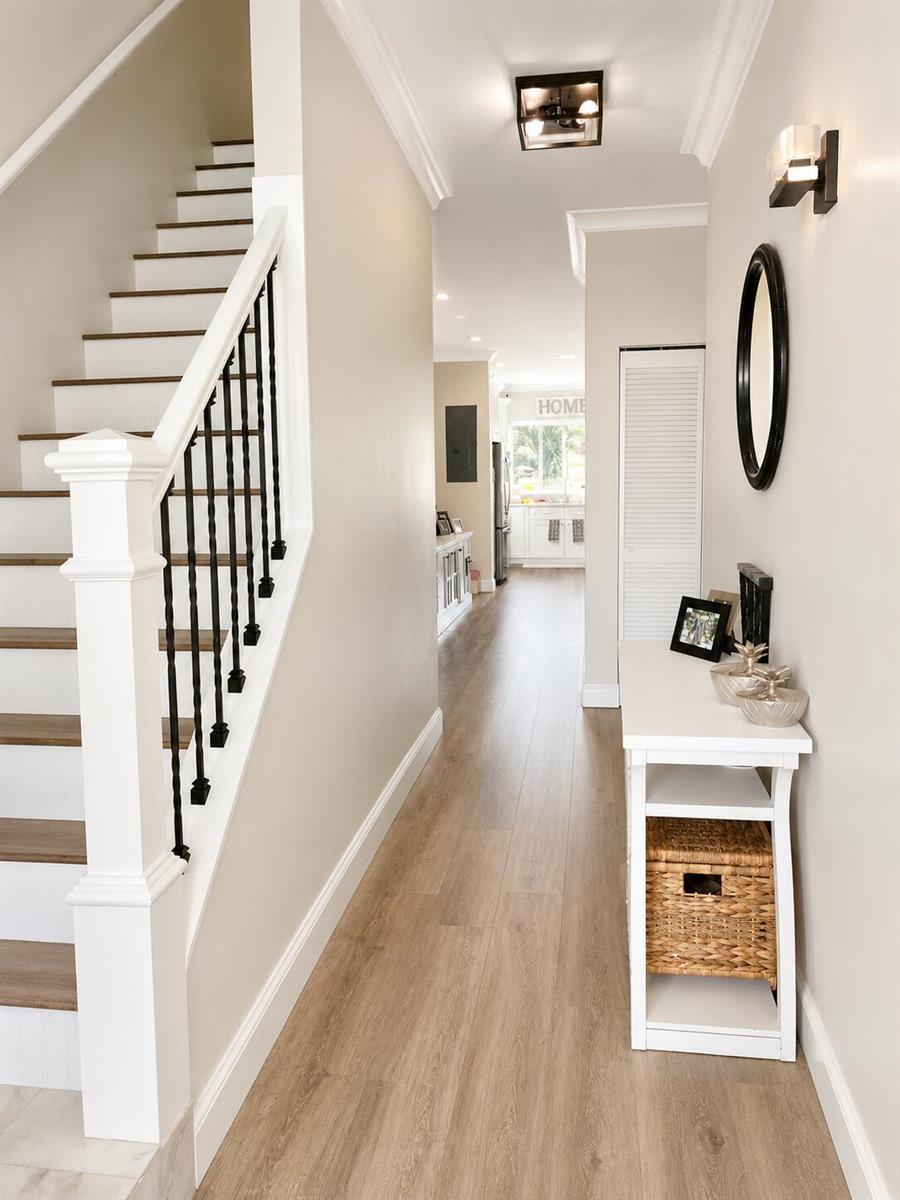 A bright hallway features wood-look flooring, a staircase with black railings, and a white console — 2305 Florida Boulevard # 2305, Delray Beach FL 33483, DELRAY BEACH, FL