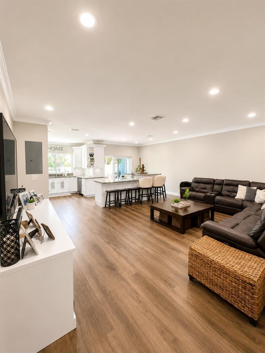 An open-concept living room features wood-look flooring, a dark leather sectional, and a kitchen island — 2305 Florida Boulevard # 2305, Delray Beach FL 33483, DELRAY BEACH, FL