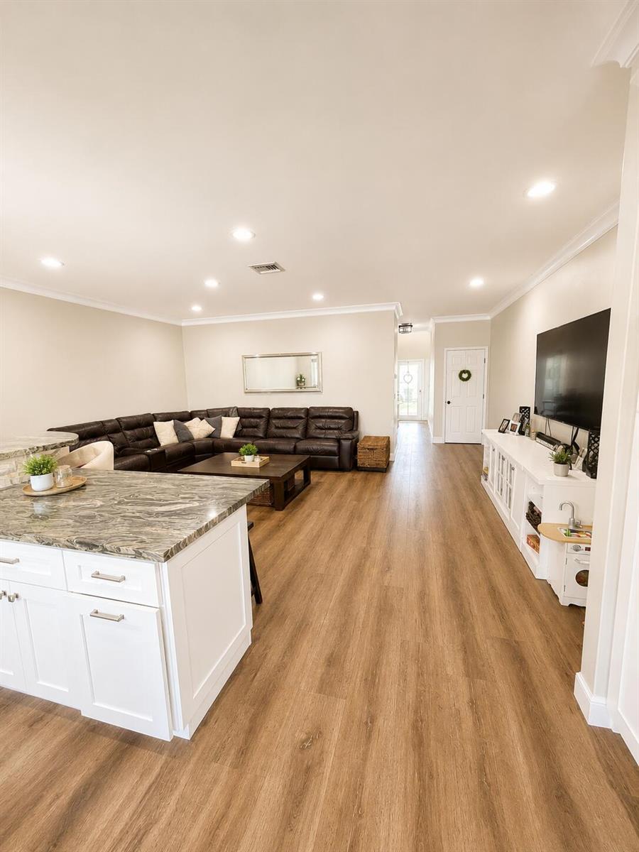 An open-concept living room features a large sectional sofa, a white media console, and wood-look flooring — 2305 Florida Boulevard # 2305, Delray Beach FL 33483, DELRAY BEACH, FL