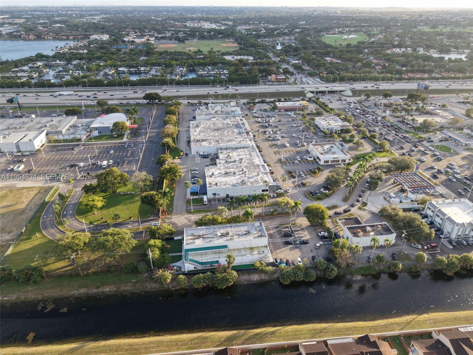 Aerial view of a commercial complex with parking lots and a canal in Florida — 6545 NW 169th St, Hialeah FL 33015, HIALEAH, FL