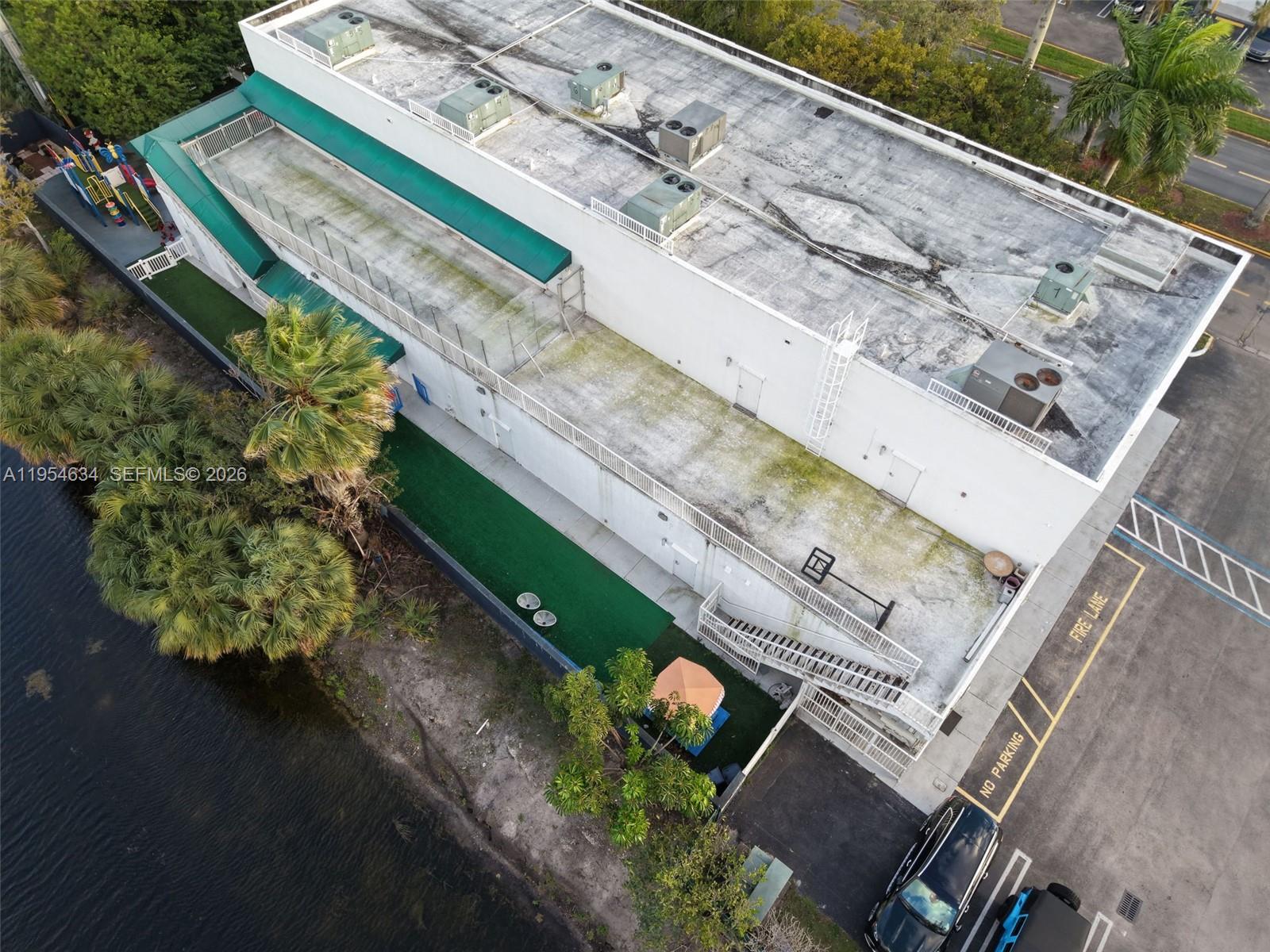 An aerial view shows a commercial building with a flat roof, HVAC units, and outdoor play area — 6545 NW 169th St, Hialeah FL 33015, HIALEAH, FL