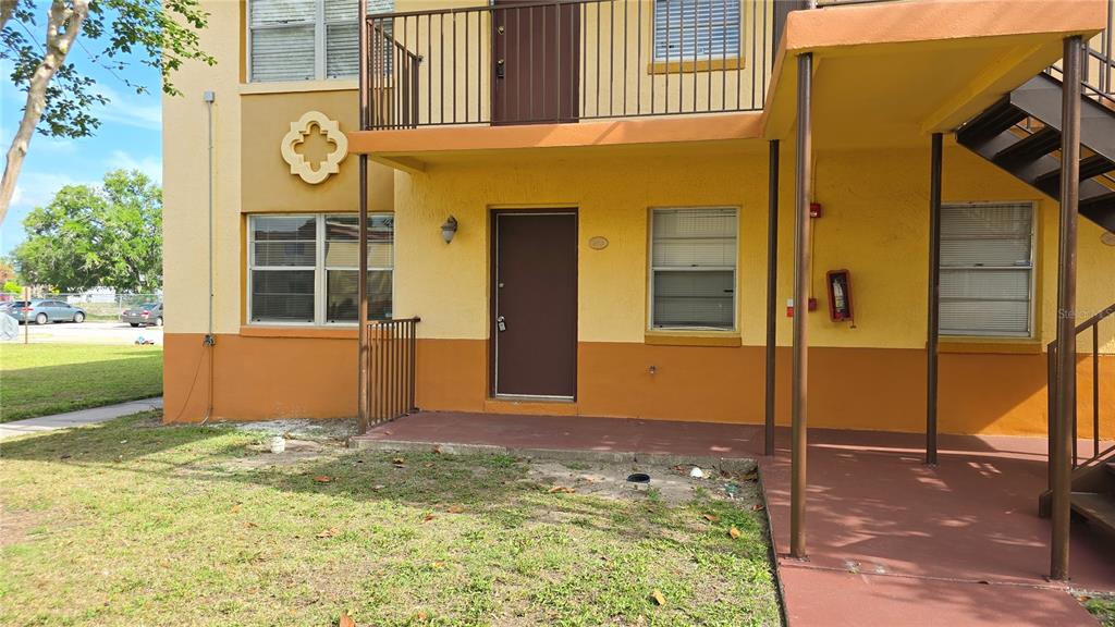 A two-story apartment building exterior features a ground-level patio, a brown door, and metal stairs — 719 WYMAN COURT UNIT 719 B, ORLANDO, FL