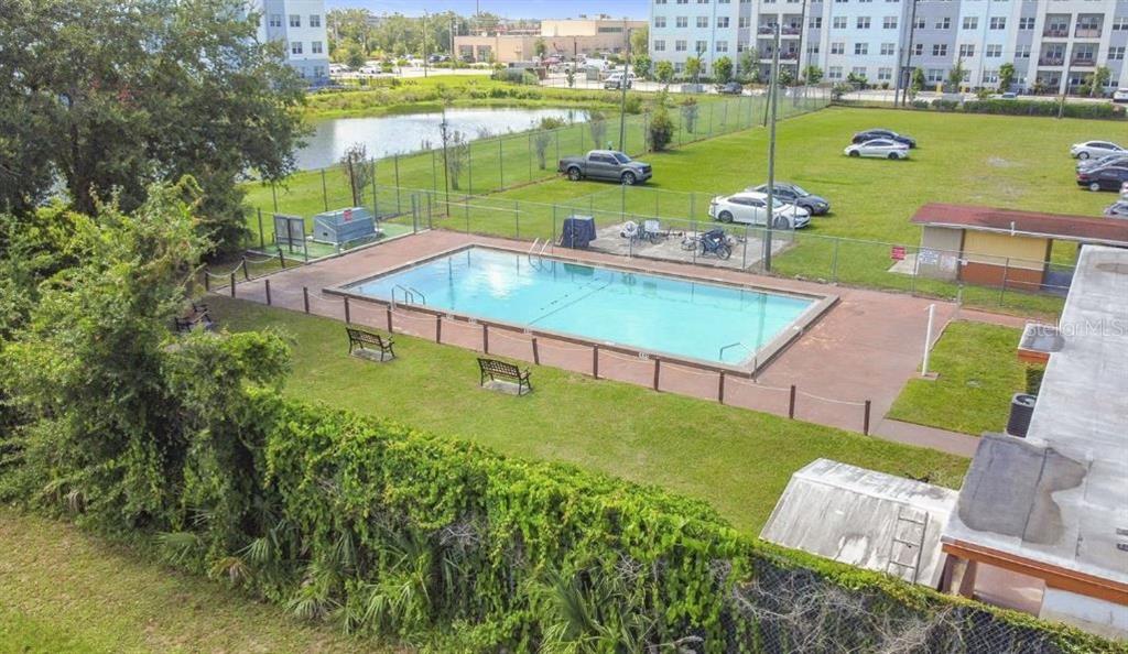 An elevated view of a rectangular swimming pool enclosed by a fence near a parking lot — 719 WYMAN COURT UNIT 719 B, ORLANDO, FL