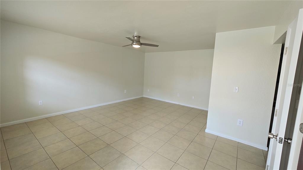 An empty room features light-colored tile flooring, off-white walls, and a ceiling fan — 719 WYMAN COURT UNIT 719 B, ORLANDO, FL