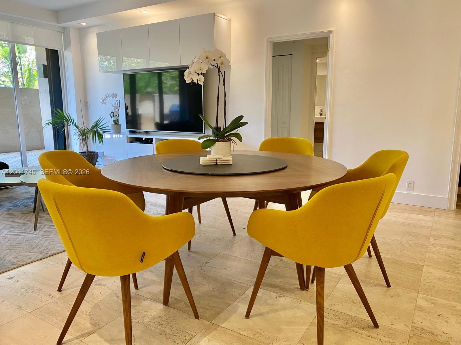 A dining area features a round wooden table with yellow chairs on tiled floors — 251 Crandon Blvd # 139, Key Biscayne FL 33149, KEY BISCAYNE, FL