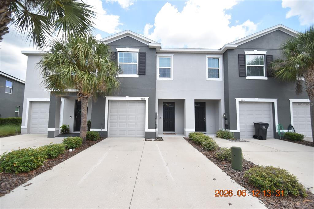 A multi-unit residential building with gray stucco facades, attached garages, and concrete driveways — 8868 INDIGO TRAIL LOOP UNIT 8868, RIVERVIEW, FL