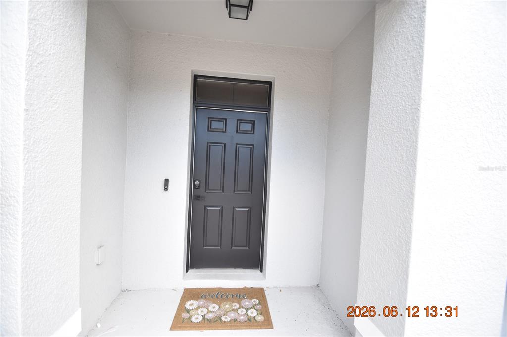 A dark gray front door with a transom window is set within a white entryway — 8868 INDIGO TRAIL LOOP UNIT 8868, RIVERVIEW, FL