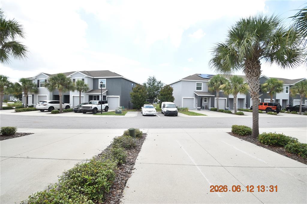 A view of a suburban street with townhouses, parked cars, and palm trees — 8868 INDIGO TRAIL LOOP UNIT 8868, RIVERVIEW, FL