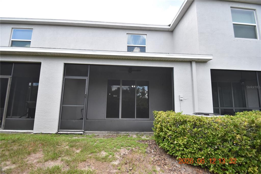 A view of a house exterior featuring a screened-in patio and a small backyard — 8868 INDIGO TRAIL LOOP UNIT 8868, RIVERVIEW, FL