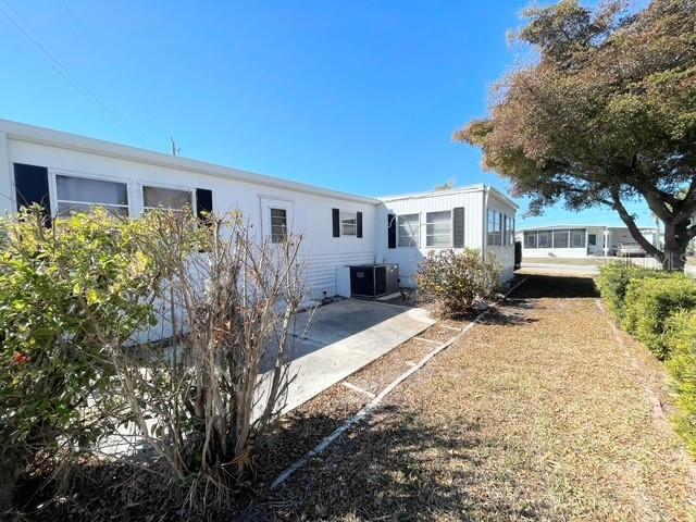 The exterior of a white mobile home features a concrete patio and an air conditioning unit — 821 TURF, VENICE, FL
