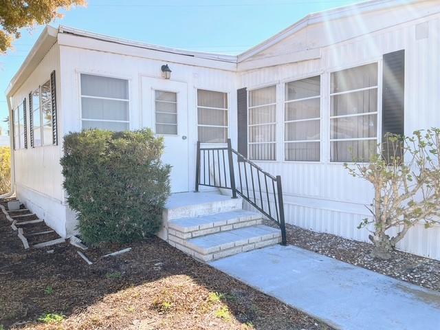 A white mobile home exterior features a small front porch with stairs and metal railings — 821 TURF, VENICE, FL