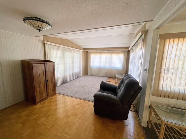 A living room features parquet wood flooring, a wooden cabinet, and a dark recliner chair — 821 TURF, VENICE, FL