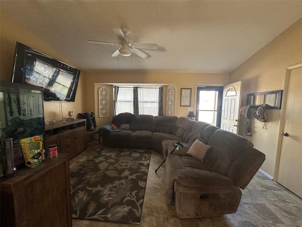 A living room features a large sectional sofa, a television, and a ceiling fan — 807 HALEYBURY STREET, PORT CHARLOTTE, FL