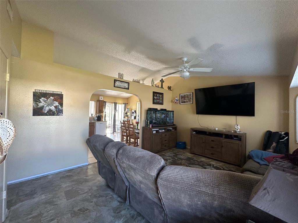 A living room features a large television, a sectional sofa, and an arched entryway — 807 HALEYBURY STREET, PORT CHARLOTTE, FL
