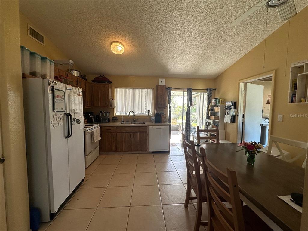 A kitchen with wood cabinets, tile flooring, and a dining area with a wooden table — 807 HALEYBURY STREET, PORT CHARLOTTE, FL