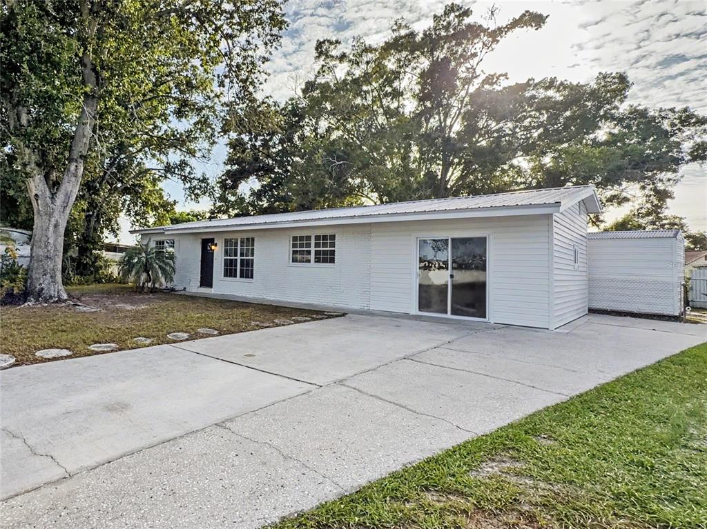 A white, single-story house with a concrete driveway and a metal roof — 6404 WILLOW BEND PLACE, TAMPA, FL