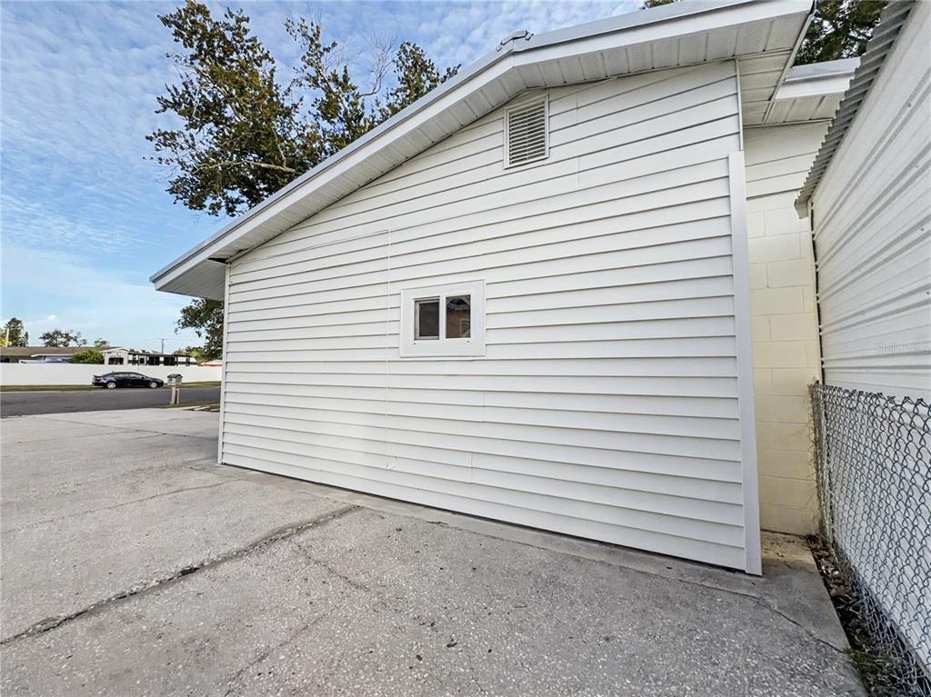 The exterior of a white-sided building features a small window and a concrete driveway — 6404 WILLOW BEND PLACE, TAMPA, FL
