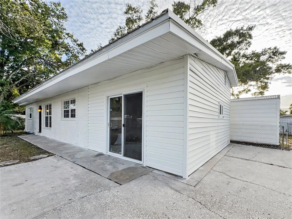 A white exterior building with a sliding glass door and a concrete patio area — 6404 WILLOW BEND PLACE, TAMPA, FL