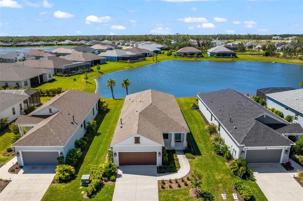 An aerial view shows a suburban house with a garage facing a pond — 14147 CAMPFIRE COURT, PARRISH, FL