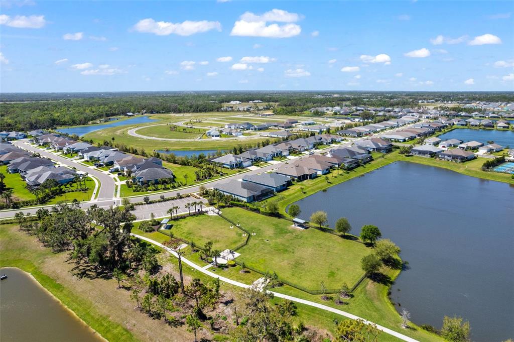 An aerial view shows a suburban neighborhood with houses, a fenced park, and retention ponds — 14147 CAMPFIRE COURT, PARRISH, FL