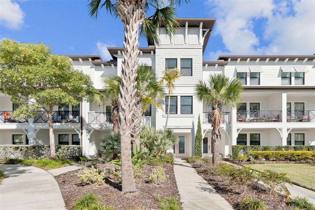 A three-story white apartment building with balconies, palm trees, and a paved walkway — 4921 W PAUL AVENUE UNIT 4, TAMPA, FL