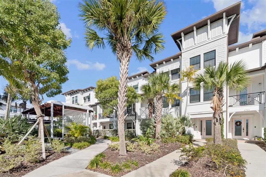 A multi-story white residential building with balconies and palm trees under a blue sky — 4921 W PAUL AVENUE UNIT 4, TAMPA, FL