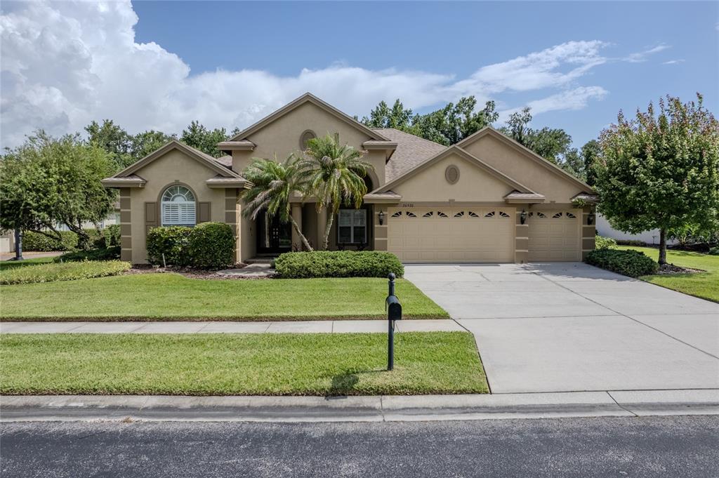 An aerial view shows a suburban house with a screened pool and a paved driveway — 26920 WINGED ELM DRIVE, WESLEY CHAPEL, FL