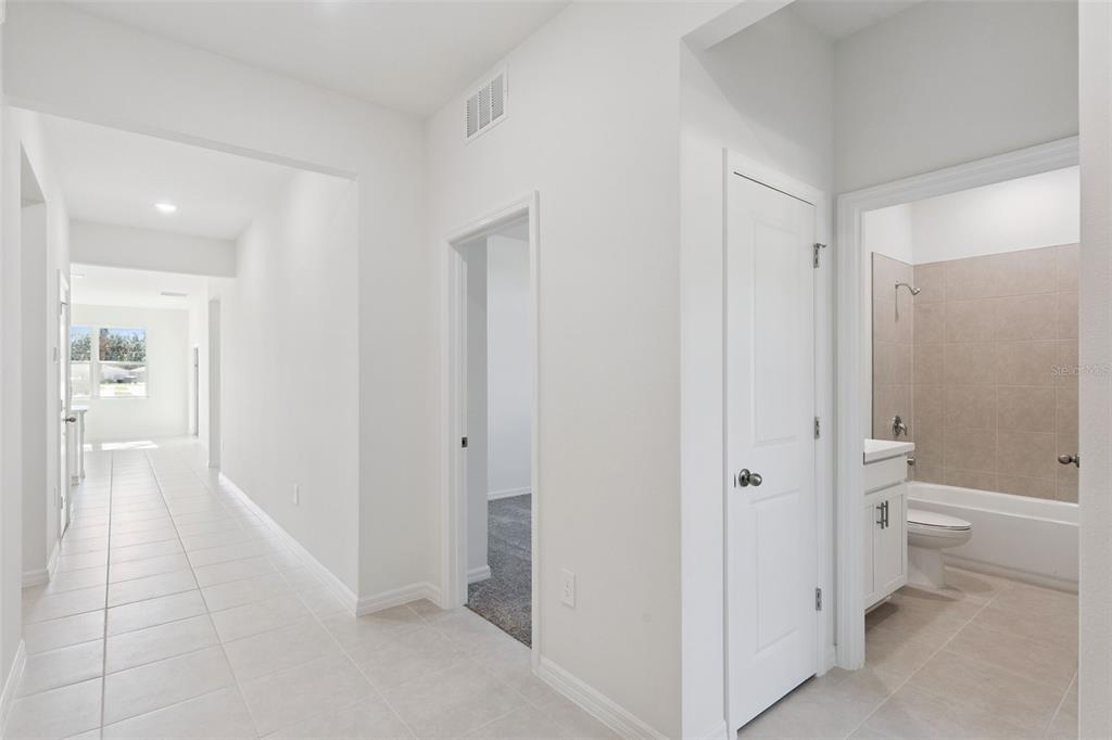 A hallway with tile flooring leads to a bathroom and a carpeted room — 4300 DARBY COURT, EUSTIS, FL