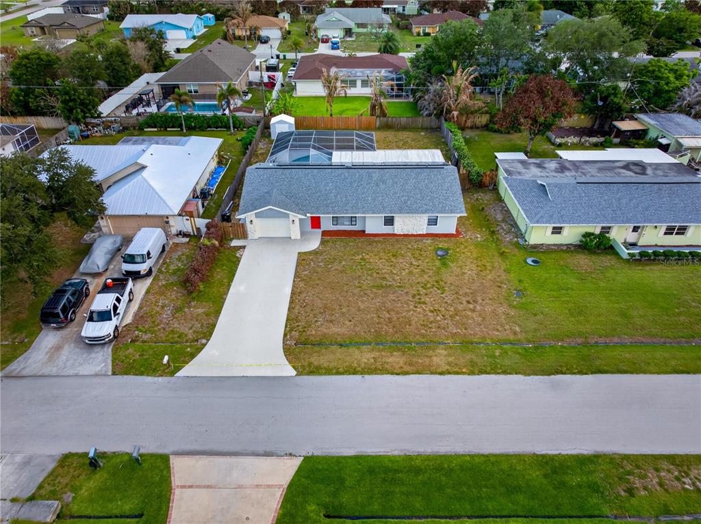 An aerial view shows a single-story house with a screened pool and a concrete driveway — 214 SE DUVAL AVENUE, PORT ST LUCIE, FL