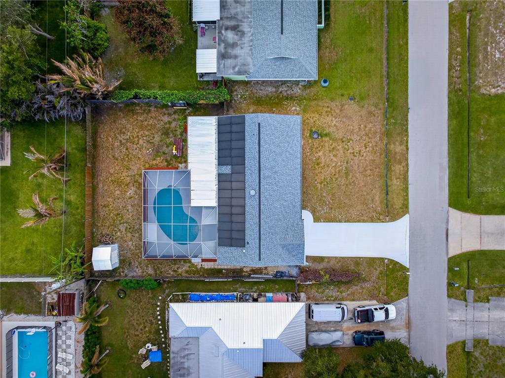 An aerial view shows a house with a pool enclosure, solar panels, and a driveway — 214 SE DUVAL AVENUE, PORT ST LUCIE, FL
