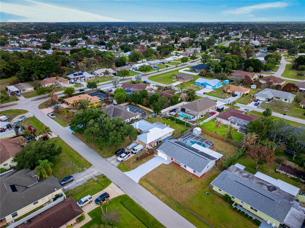 An aerial view of a suburban neighborhood featuring single-family homes with pools and paved streets — 214 SE DUVAL AVENUE, PORT ST LUCIE, FL