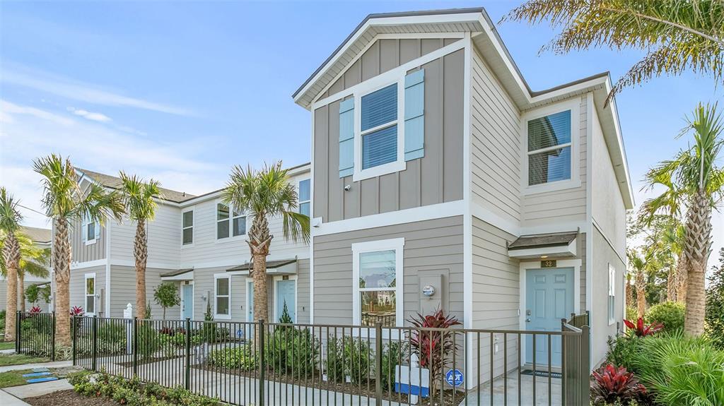A two-story townhouse with light blue doors, gray siding, and palm trees behind a fence — 332 PALMETTO RIDGE ROAD, ST AUGUSTINE, FL