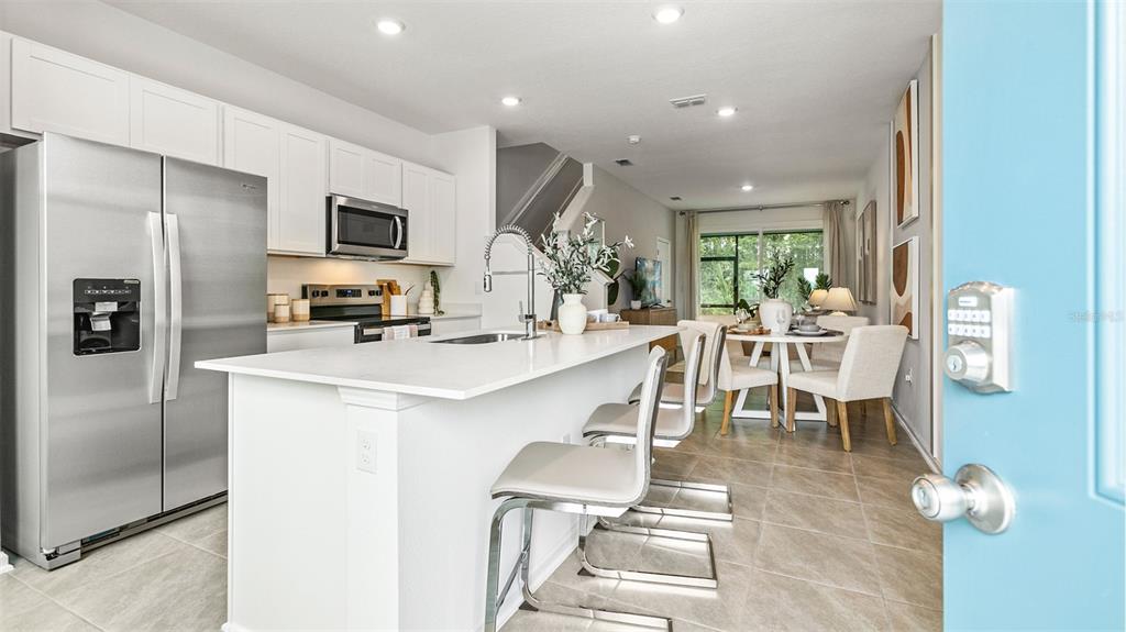 A modern kitchen with white cabinets, stainless steel appliances, and a central island with seating — 332 PALMETTO RIDGE ROAD, ST AUGUSTINE, FL