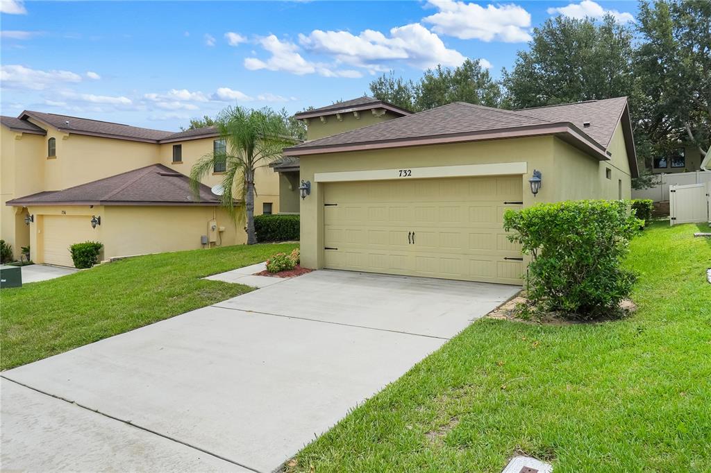 A tan single-story house with a two-car garage and a concrete driveway — 732 ARBOR POINTE AVENUE, MINNEOLA, FL